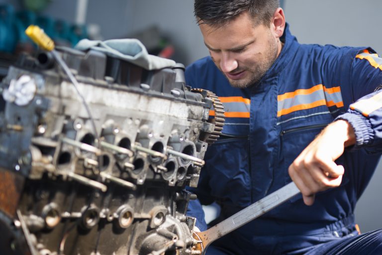 Professional car mechanic repairing automobile engine using wrench in work shop. Professional car mechanic repairing automobile engine using wrench in work shop.